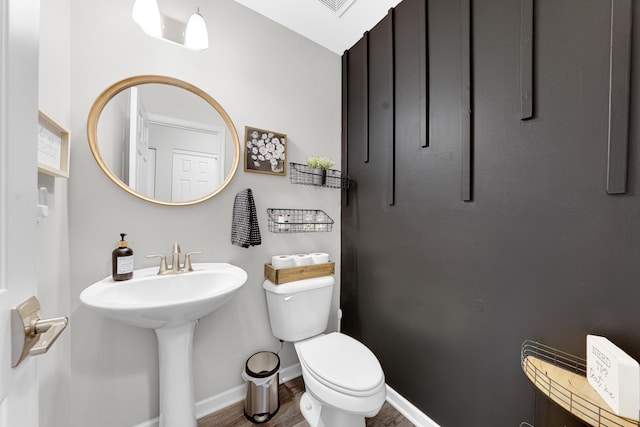 bathroom with toilet, wood finished floors, and baseboards
