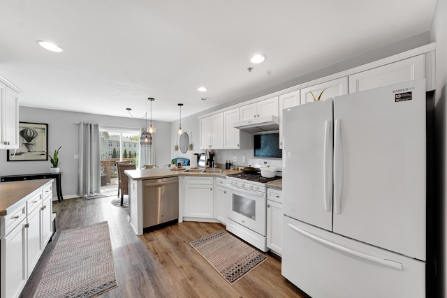 kitchen featuring white appliances, a peninsula, under cabinet range hood, white cabinetry, and wood finished floors
