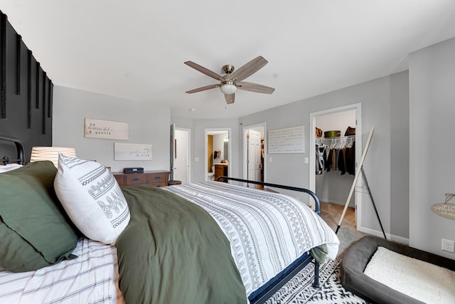 bedroom with a walk in closet, light carpet, a closet, baseboards, and a ceiling fan