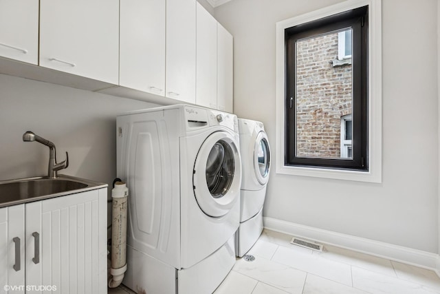 washroom with washer and dryer, cabinet space, and baseboards