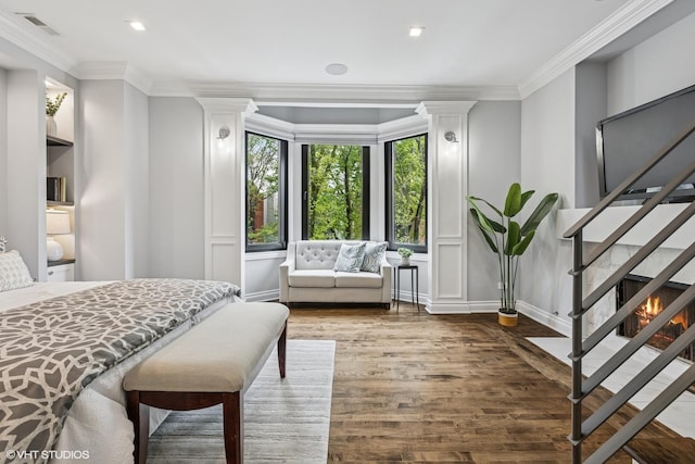 bedroom featuring wood finished floors, ornamental molding, a decorative wall, and recessed lighting