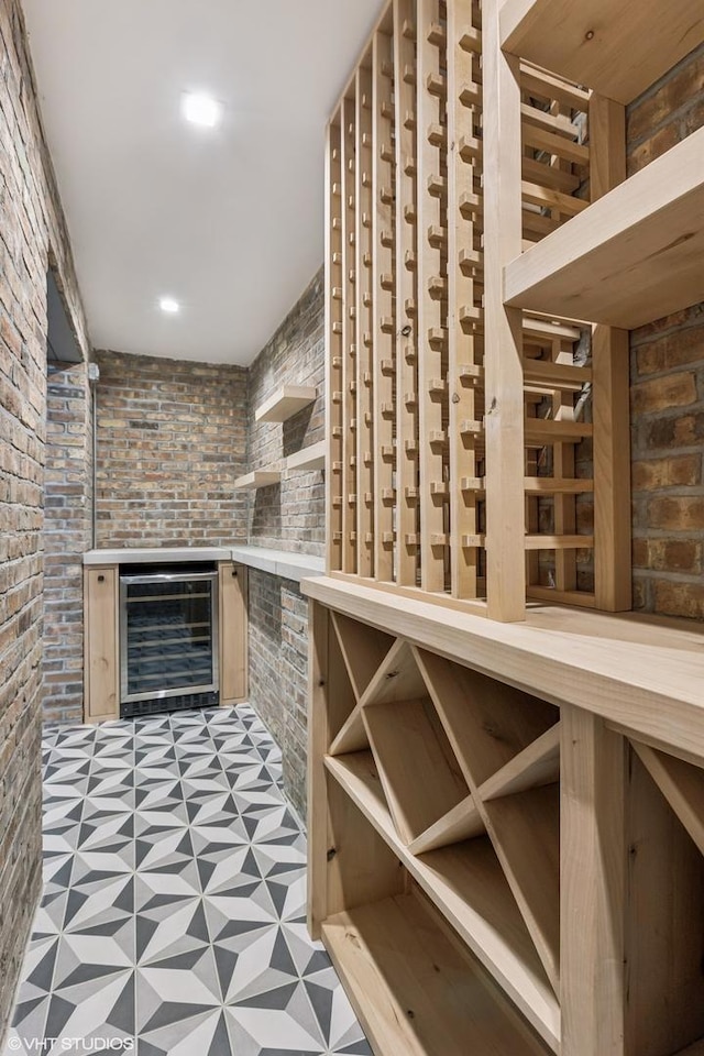 wine cellar featuring beverage cooler, tile patterned floors, brick wall, and a fireplace