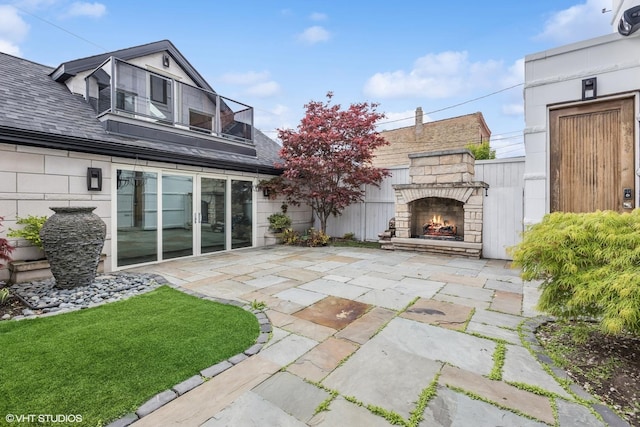 back of property featuring an outdoor stone fireplace, a patio area, and stone siding