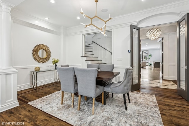 dining area featuring decorative columns, stairway, a chandelier, crown molding, and wood finished floors