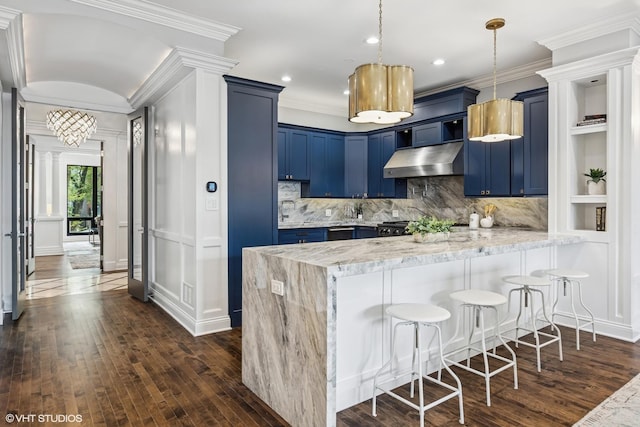 kitchen with blue cabinets, under cabinet range hood, a peninsula, crown molding, and dark wood-style floors