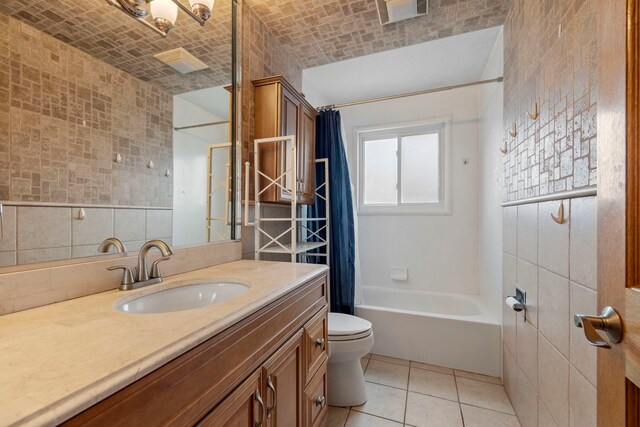 full bathroom with tile walls, toilet, vanity, tile patterned flooring, and shower / bath combo with shower curtain