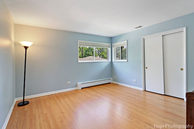 1129 Longmeadow Dr, Glenview, IL 60025 - unfurnished bedroom with a baseboard radiator, wood finished floors, baseboards, and a closet