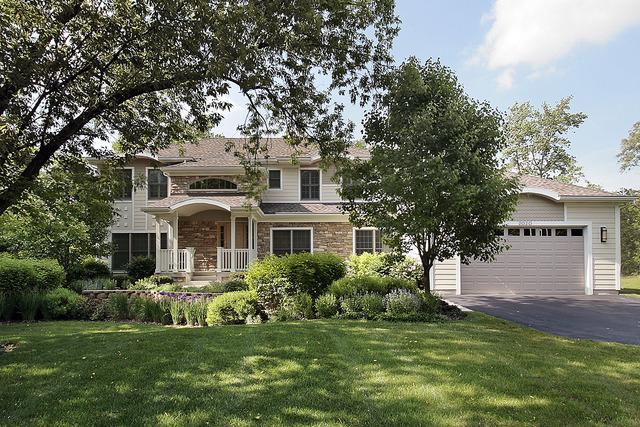 2020 Techny Rd, Northbrook, IL 60062 - shingle-style home with driveway, a front lawn, a garage, and stone siding