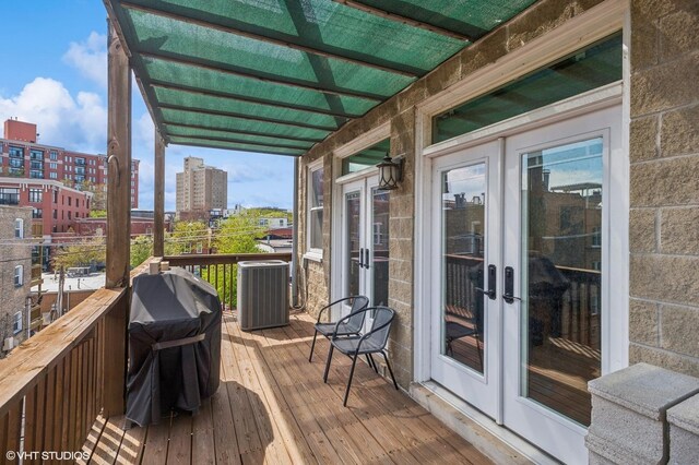wooden terrace featuring french doors, central AC unit, area for grilling, and a city view