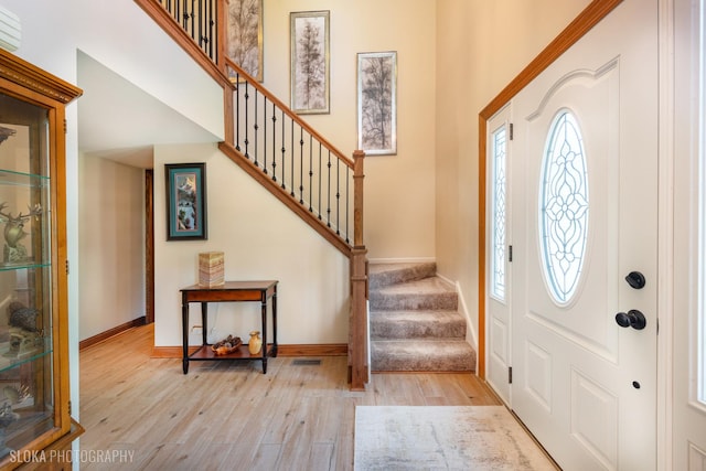 foyer with wood-type flooring, stairway, and baseboards