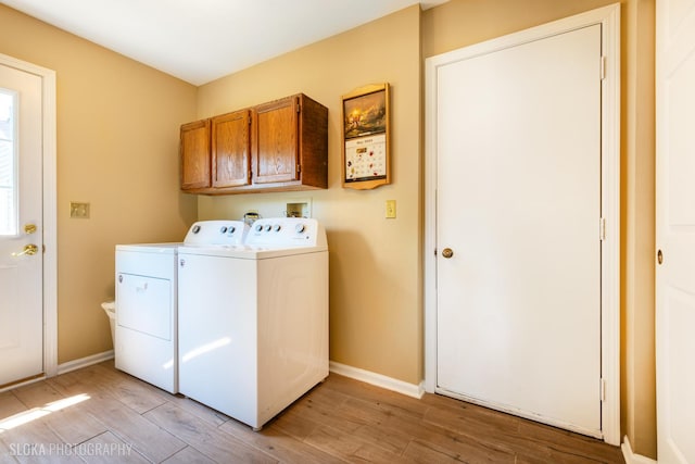 laundry room with cabinet space, washing machine and dryer, light wood finished floors, and baseboards
