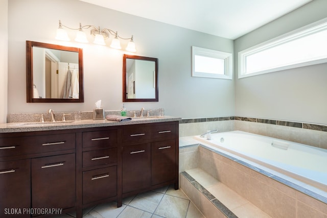 bathroom with a bath, double vanity, and tile patterned flooring