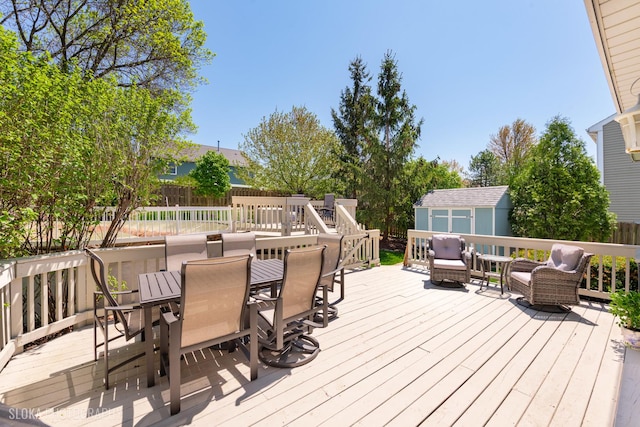 wooden deck featuring a storage shed, outdoor dining area, an outbuilding, and fence