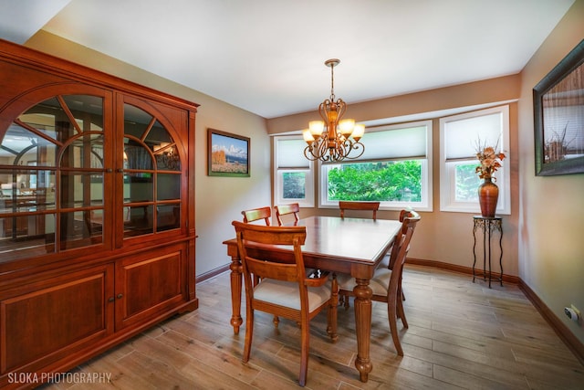 dining room with a chandelier, baseboards, and light wood finished floors
