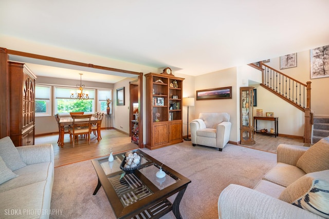 living room with a chandelier, light colored carpet, stairs, baseboards, and light wood-style floors