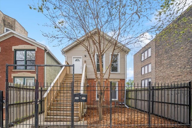 view of front of house featuring a gate, a fenced front yard, brick siding, and stairway