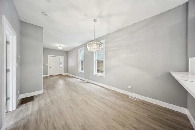 unfurnished dining area featuring baseboards, wood finished floors, and a chandelier