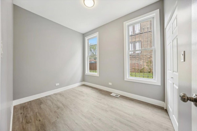 spare room featuring light wood-style floors and baseboards