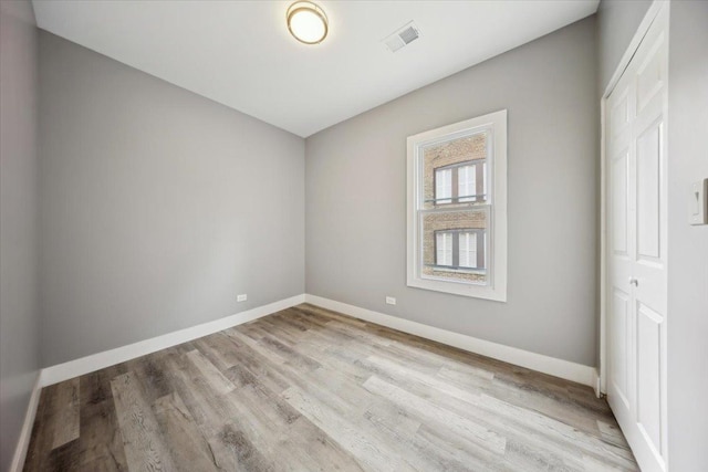 spare room with baseboards and wood finished floors