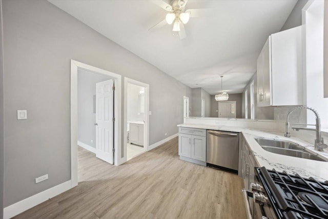kitchen with a sink, appliances with stainless steel finishes, a peninsula, and light wood-style flooring