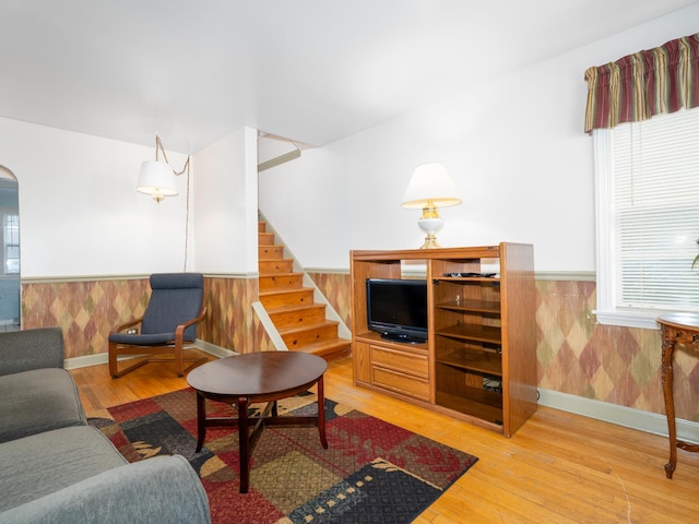 2504 W St, River Grove, IL 60171 - living room featuring wainscoting, stairway, light wood-style flooring, arched walkways, and baseboards