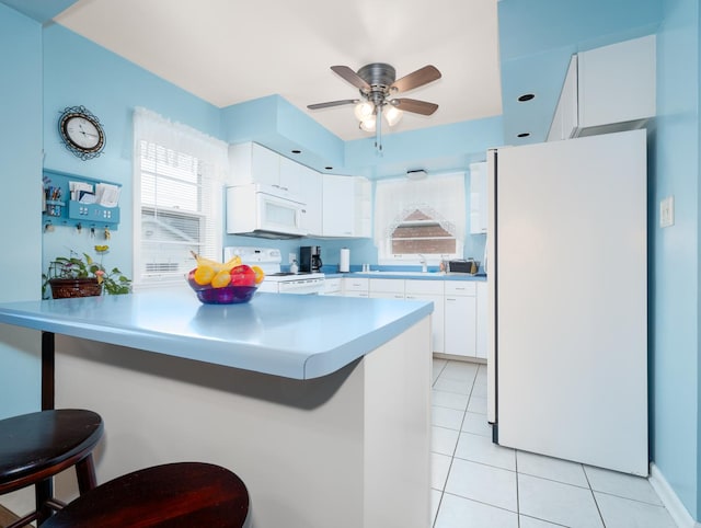 2504 W St, River Grove, IL 60171 - kitchen with white appliances, a kitchen breakfast bar, light tile patterned floors, and white cabinets
