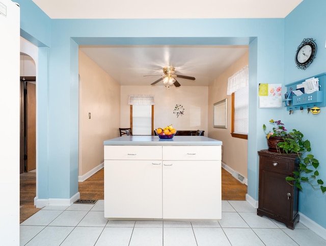 2504 W St, River Grove, IL 60171 - kitchen with ceiling fan, white cabinetry, baseboards, arched walkways, and a kitchen island