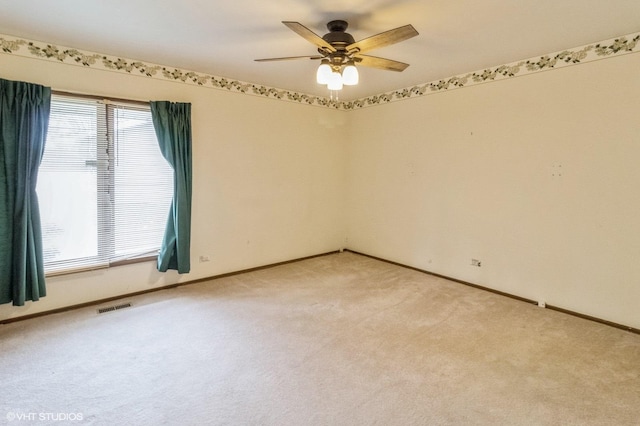 unfurnished room with light colored carpet, a ceiling fan, and baseboards