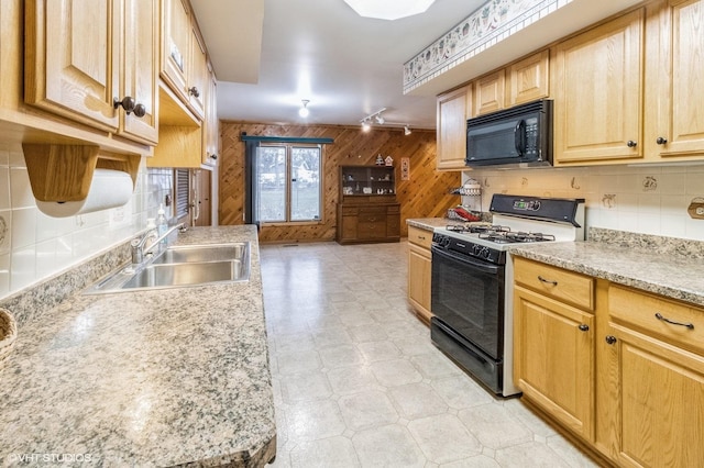 kitchen featuring black appliances, a sink, wood walls, light flooring, and light brown cabinets
