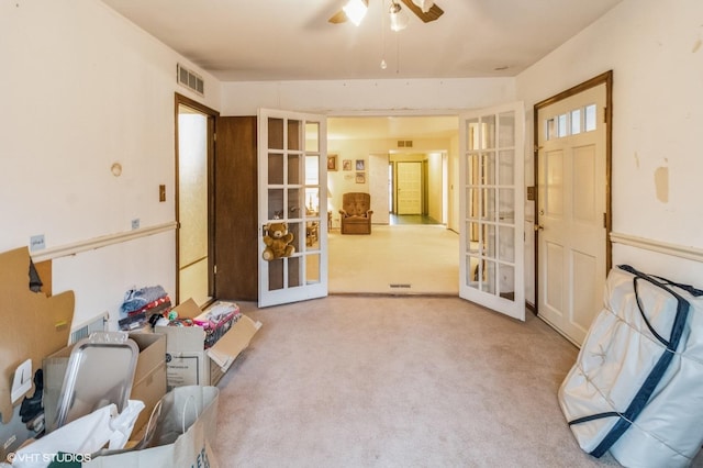 foyer with french doors, ceiling fan, and carpet