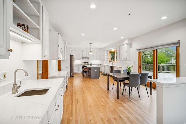 kitchen with a sink, stainless steel appliances, light wood-style flooring, white cabinetry, and recessed lighting