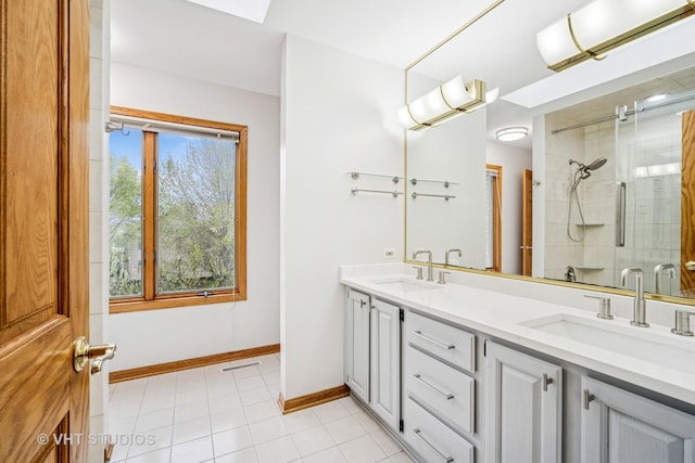 bathroom with a stall shower, baseboards, tile patterned floors, and double vanity