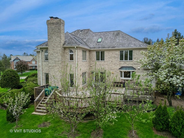 back of house with a chimney, brick siding, and a wooden deck