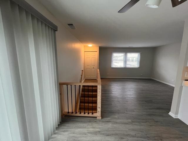 spare room featuring ceiling fan, baseboards, wood finished floors, and stairs