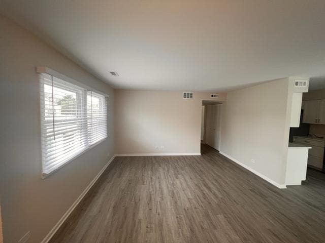 unfurnished living room featuring dark wood-type flooring and baseboards