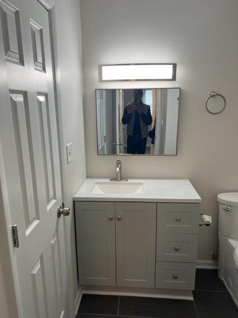 bathroom with toilet, tile patterned floors, and vanity