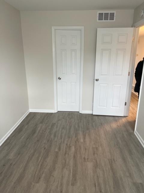 unfurnished bedroom featuring baseboards and dark wood-style flooring