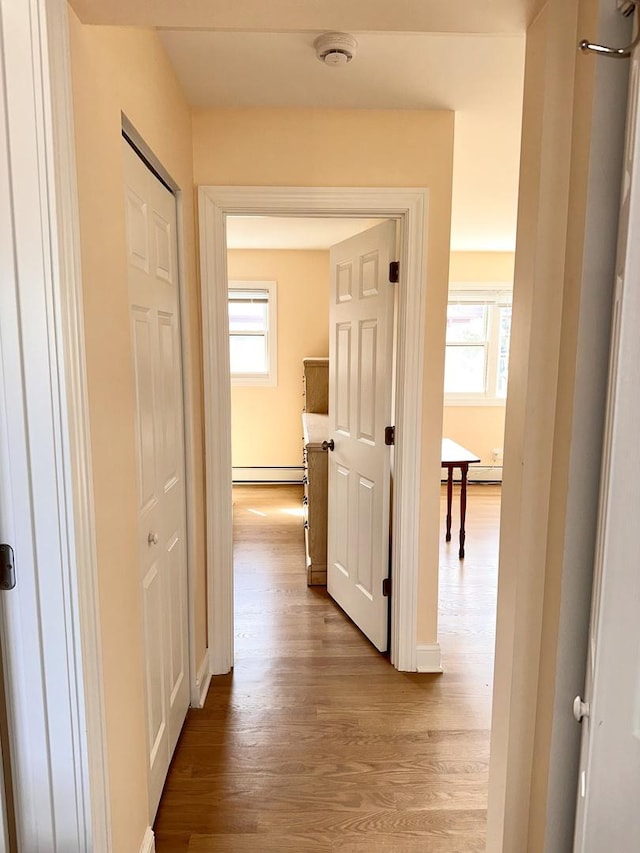 hallway featuring wood finished floors, baseboards, and baseboard heating