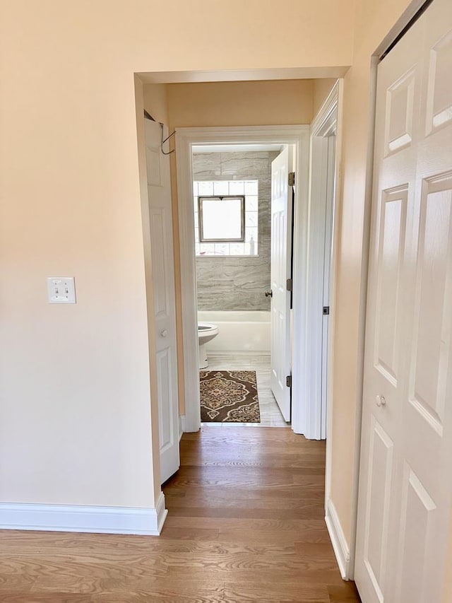 corridor with baseboards and wood finished floors