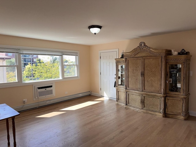 empty room with a wall mounted AC, light wood-style flooring, a baseboard radiator, and baseboards