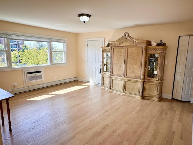 unfurnished living room featuring a baseboard heating unit, an AC wall unit, light wood-style floors, and baseboards