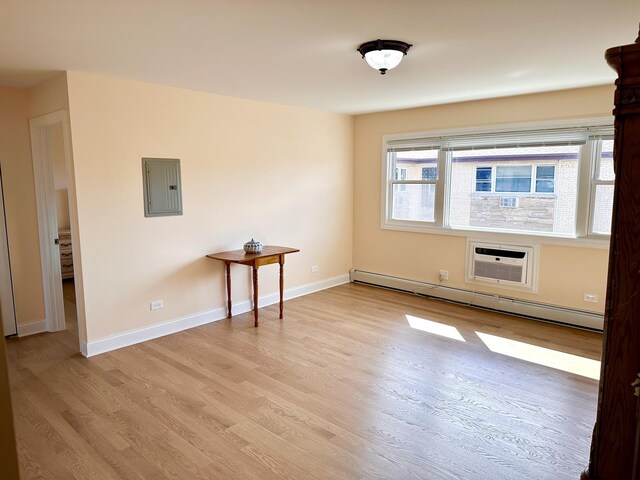 empty room with baseboard heating, electric panel, light wood-style floors, an AC wall unit, and baseboards