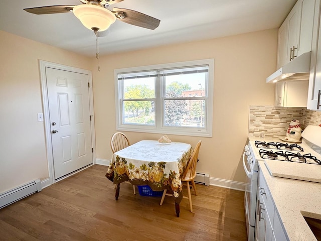 dining area featuring a baseboard radiator, ceiling fan, wood finished floors, and baseboards
