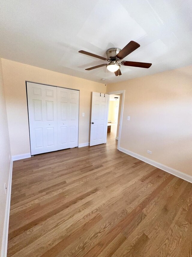 unfurnished bedroom featuring baseboards, light wood-style flooring, a closet, and ceiling fan