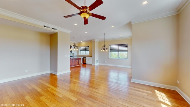unfurnished living room featuring a chandelier, light wood-style flooring, crown molding, a ceiling fan, and baseboards