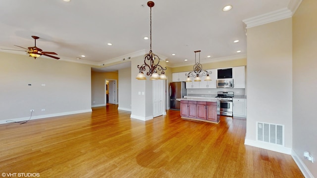 kitchen featuring stainless steel appliances, open floor plan, a kitchen island, light wood-style flooring, and light countertops