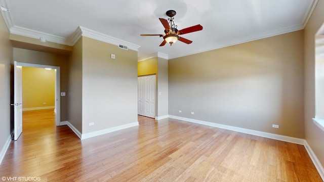empty room with a ceiling fan, light wood-style flooring, crown molding, and baseboards