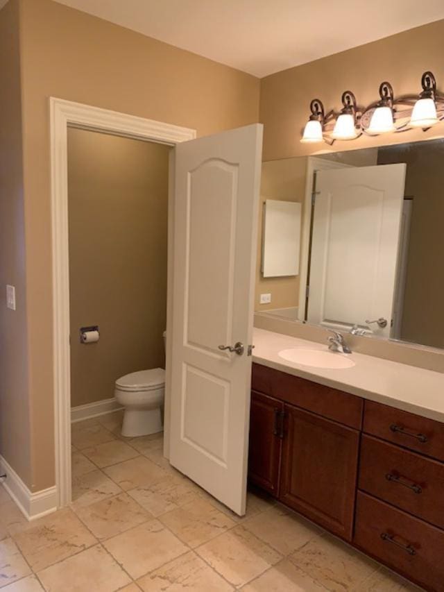 bathroom featuring toilet, vanity, and baseboards