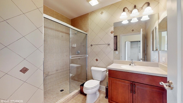 bathroom featuring tile walls, a stall shower, toilet, vanity, and tile patterned floors