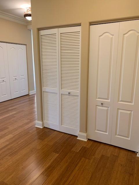 unfurnished bedroom featuring wood finished floors, crown molding, and baseboards